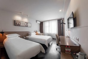 Hotelkamer met twee bedden, een bureau, een stoel, een televisie en een raam met gordijnen.