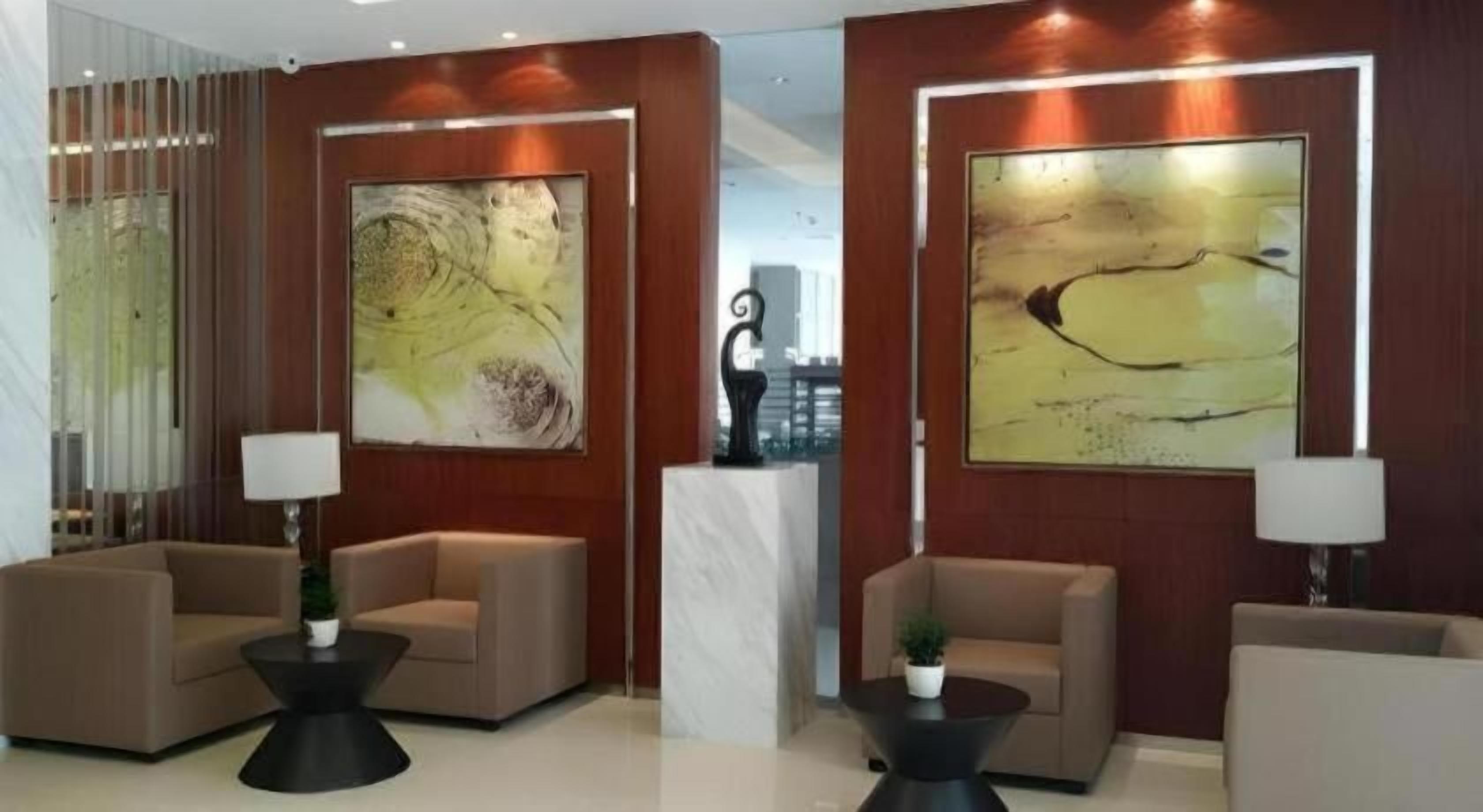 A lobby with seating arrangements, a reception desk, and abstract wall art.