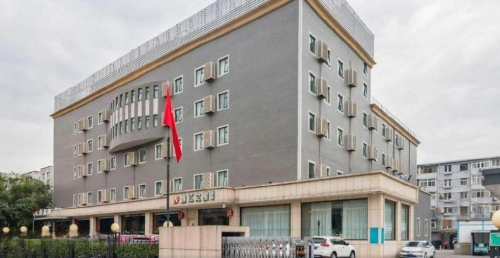 Ein mehrstöckiges Gebäude mit flacher Fassade, Klimaanlagen und einer Fahne auf einem Fahnenmast.