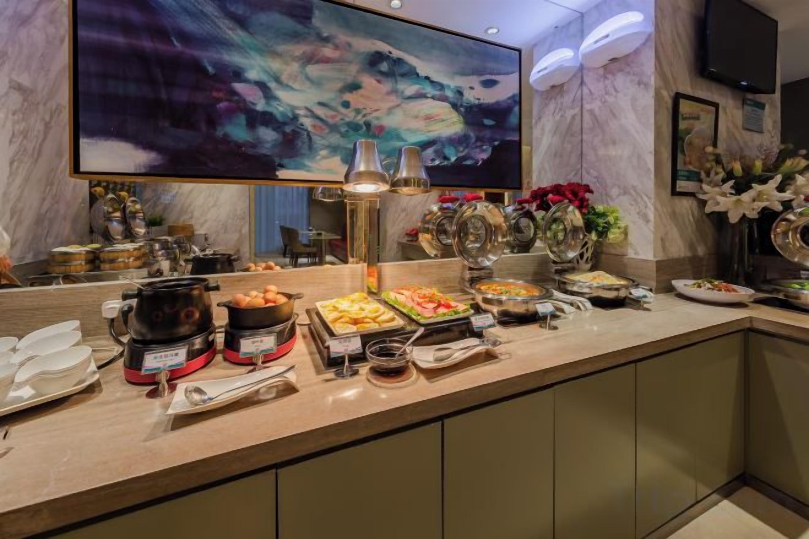 A buffet with various food items and a large abstract painting on the wall.