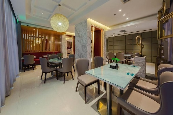 A modern hotel dining area with a glass table, leather chairs, and a decorative hanging light fixture. - Jinjiang Inn Select (Beijing Wukesong) (Beijing)