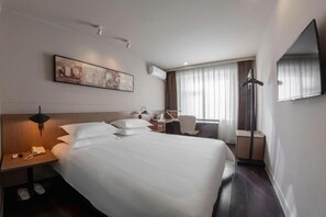 A hotel room with a large bed, a desk, a chair, a flat-screen TV, a coat rack, and a painting on the wall. - Jinjiang Inn Select (Beijing Wukesong) (Beijing)