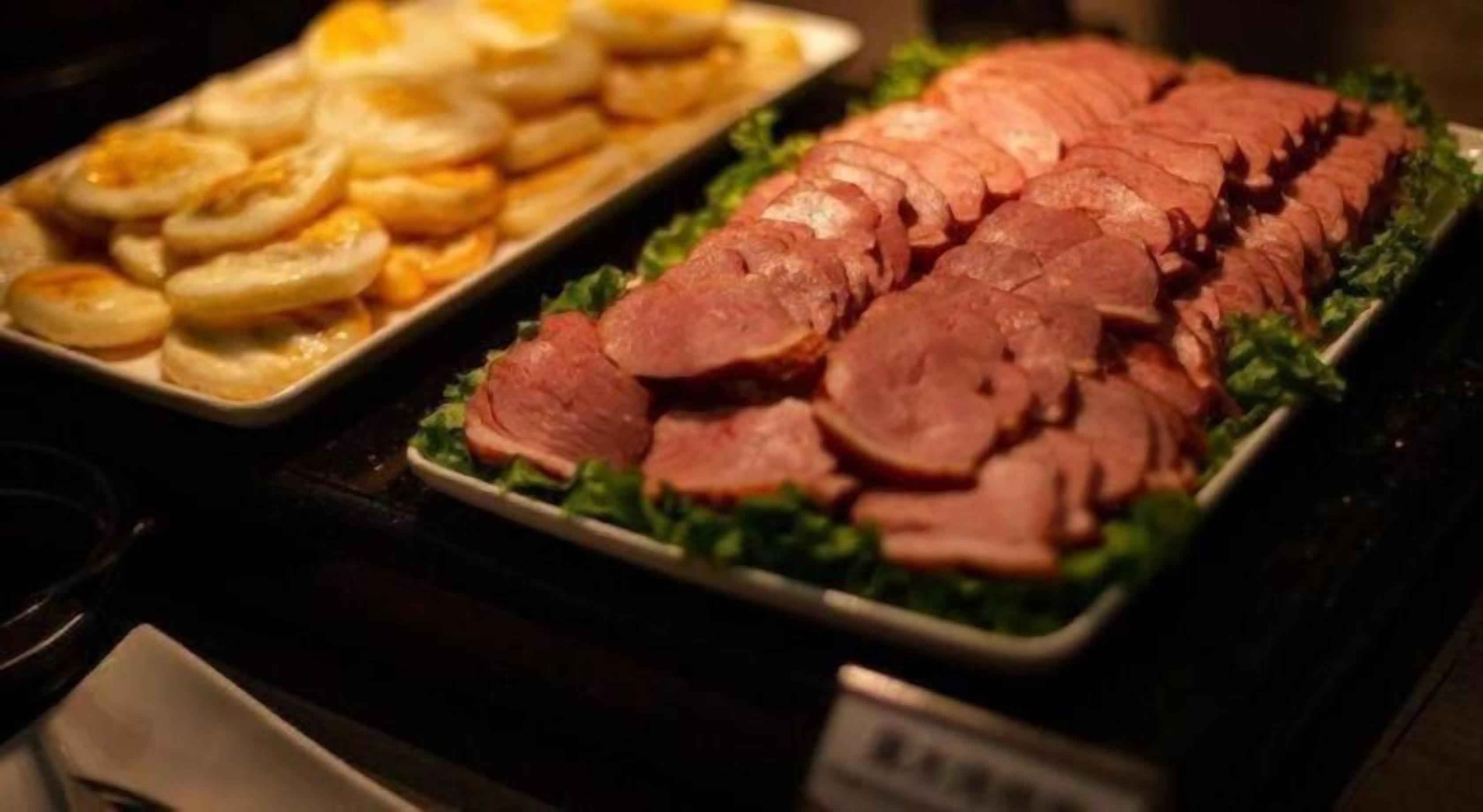 Un bufé con carnes en rodajas y pasteles.