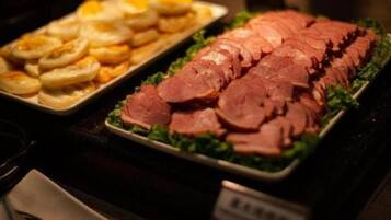 Un bufé con carnes en rodajas y pasteles.