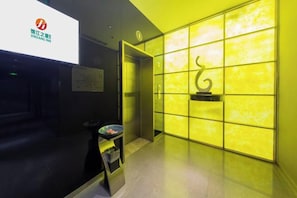 A hotel reception area with a modern design, featuring a reception desk, a digital screen, and a wall with a geometric pattern. - Jinjiang Inn Select (Beijing Wukesong) (Beijing)
