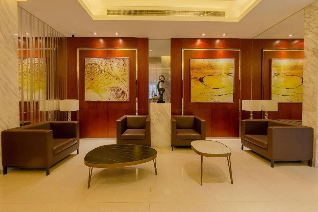 A lobby with a reception desk, two sofas, a coffee table, and abstract paintings on the walls.
