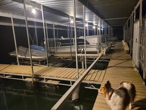 A marina with boats docked under a covered area with a wooden deck. - Beautiful Home on 18 acres with view of Beaver Lake and lake access. (Rogers)