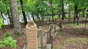 A wooden structure with rope barriers in a forested area near a body of water.