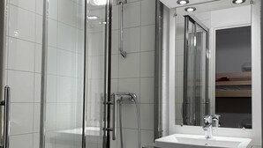 A modern bathroom with a glass-enclosed shower, a white sink, and a mirror above it. - travelski home classic - Résidence La Muzelle. (Les Deux Alpes)