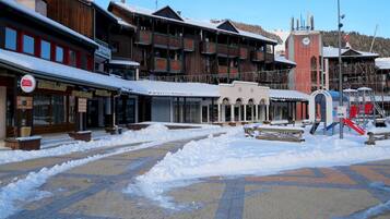 A snow-covered plaza with buildings, including a restaurant and a hotel.