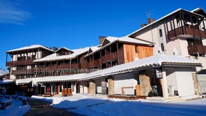 A multi-story hotel with balconies, a ski lift, and a snow-covered ground. - travelski home classic - Résidence La Muzelle. (Les Deux Alpes)