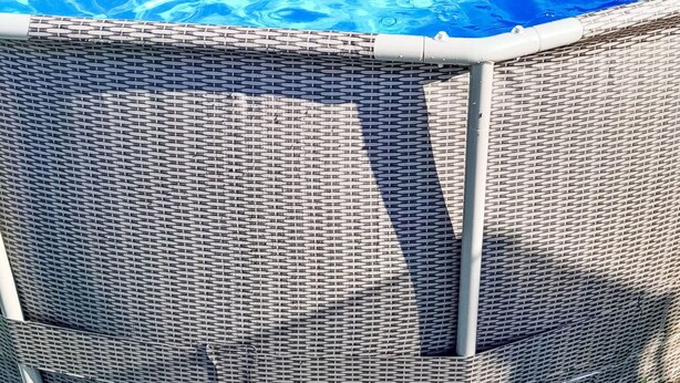 Una piscina rodona sobre terra amb una tanca de vimet per seguretat.