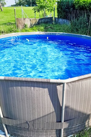 Una piscina rodona sobre terra amb una tanca de vimet per seguretat.