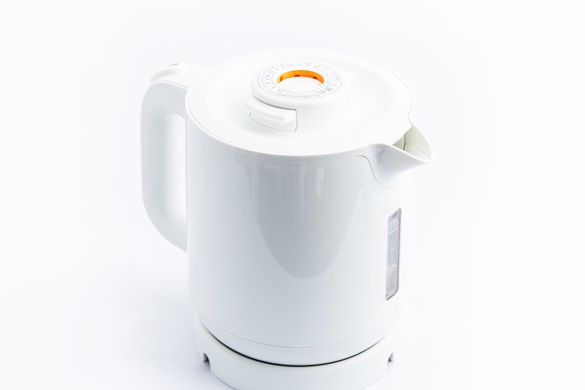 A white electric kettle with a handle and a spout, featuring a control dial and a power indicator.