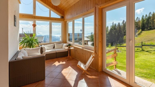 Ein geräumiger Raum mit großem Fenster und Blick auf eine grüne Landschaft und Berge.
