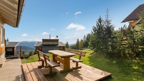 Eine Holterrasse mit Picknicktisch und Bänken, mit Blick auf eine gebirgige Landschaft.