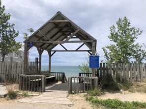 A wooden gazebo with a beach view, a wooden fence, and a sign with beach rules.