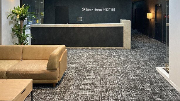 A reception area with a sofa, a reception desk, and a plant. - Santiago Hotel (Hiroshima)