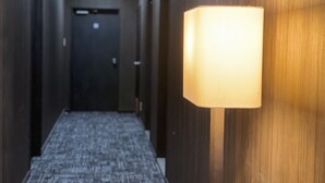 A hallway with wooden walls and a carpeted floor, leading to a door at the end. - Santiago Hotel (Hiroshima)