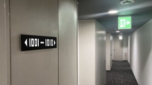 A hallway with directional signs and an emergency exit sign. - Santiago Hotel (Hiroshima)