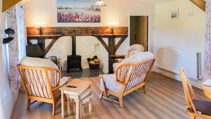 A cozy room with wooden furniture, a fireplace, and a painting on the wall. - 2 bedroom accommodation in Carmel, near Caernarfon (Carmel, near Caernarfon)
