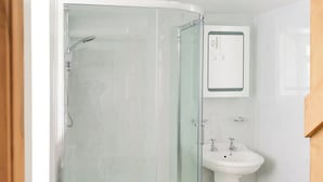 A bathroom with a glass-enclosed shower, a pedestal sink, and a mirror above the sink. - 2 bedroom accommodation in Carmel, near Caernarfon (Carmel, near Caernarfon)