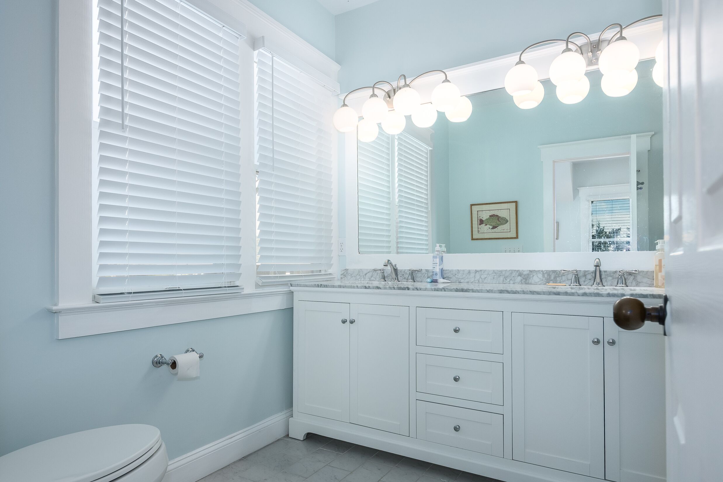 Une salle de bain avec des meubles blancs, un lavabo et des toilettes.