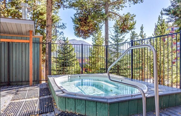 Relax in the hot tub surrounded by a mountain view and a wooden deck.