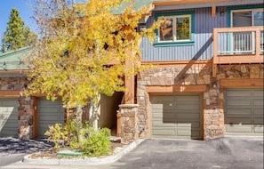 Two-story home with a flat roof and stone facade, featuring a small porch and two garage doors.