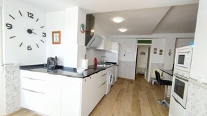 A modern kitchen with white cabinets, a black countertop, and a built-in washing machine.