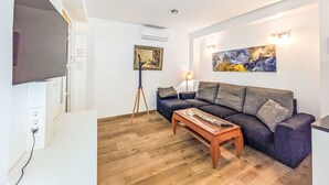 A living room with a sofa, a coffee table, a TV, a painting, and a lamp.