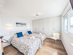 Une chambre avec deux lits, une chaise, une armoire, un tableau et une fenêtre.