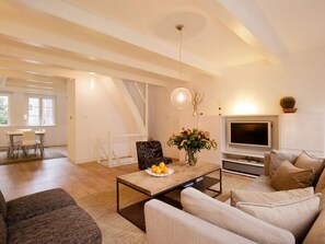 Relax in this stylish living room with a comfortable sofa, flat-screen TV, and dining area.