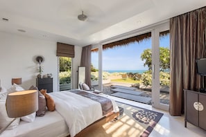 A bedroom with a large bed, a TV, and a view of the ocean. - Sangsuri Villa 1 (Koh Samui)