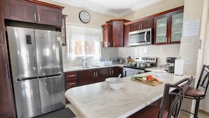 Una cocina moderna con electrodomésticos de acero inoxidable, armarios de madera y una encimera de mármol.