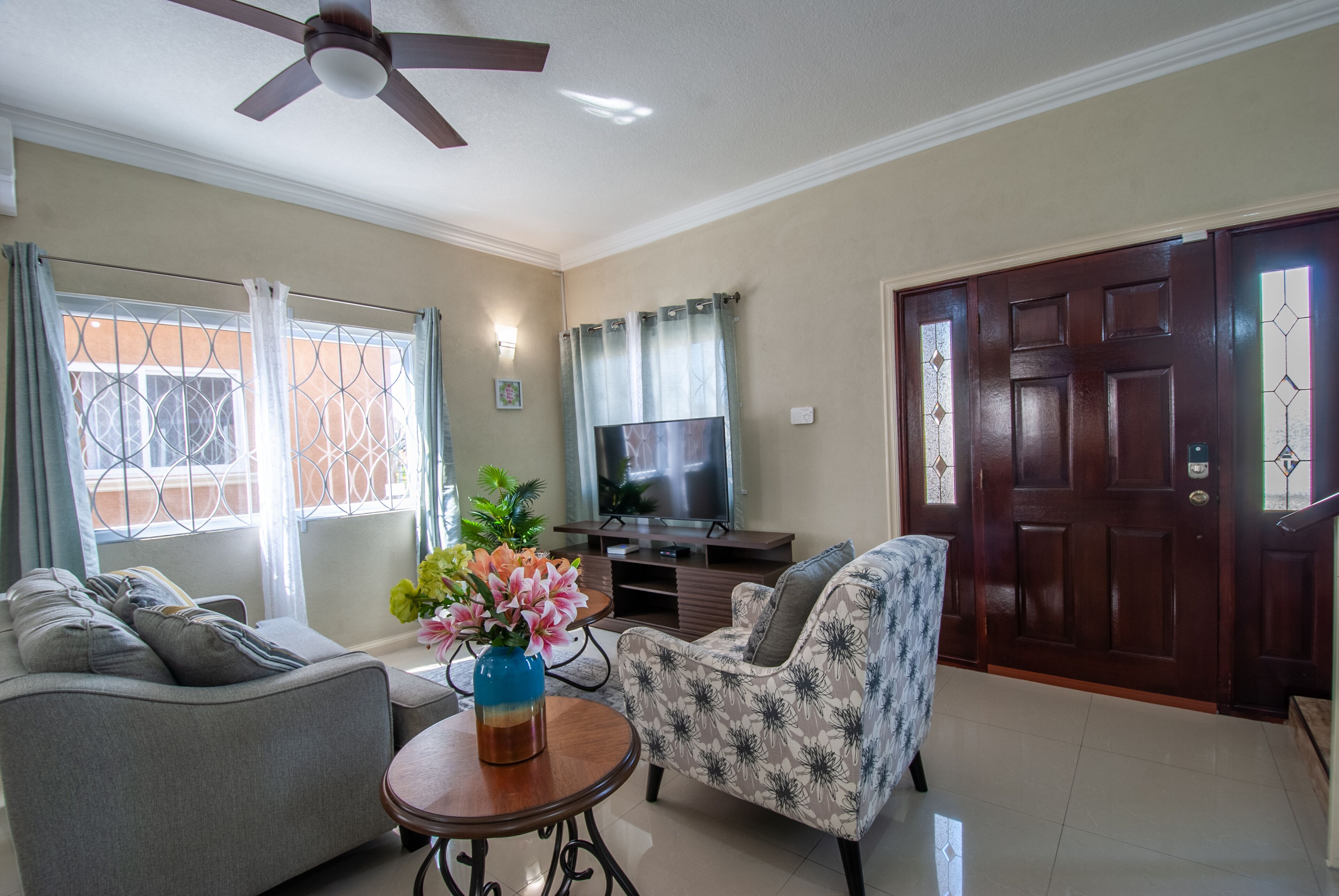 A living room with a sofa, armchair, TV, and a decorative vase.