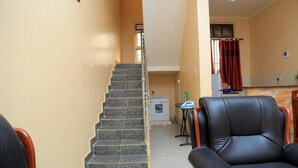 A staircase leading to a second floor, a black leather chair, and a small table with a bottle. - Apt - Sleeps 4 - Pets Ok - Parking - Garden (Kampala)