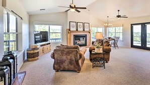 A spacious living room with a fireplace, sofas, a TV, and a ceiling fan. - Majestic Views & Wraparound Deck: Show Low Haven (Show Low)