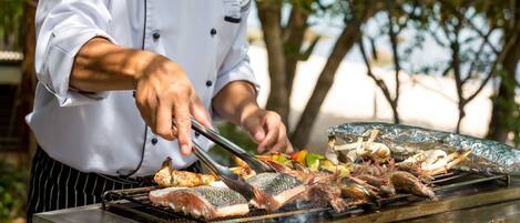 A chef grilling various seafood items outdoors.