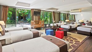 A hotel room with multiple beds, a seating area, and large windows offering a view of greenery. - Sangsuri Villa 2 (Koh Samui)