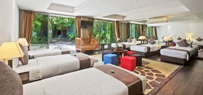 A hotel room with multiple beds, a seating area, and large windows offering a view of greenery. - Sangsuri Villa 2 (Koh Samui)
