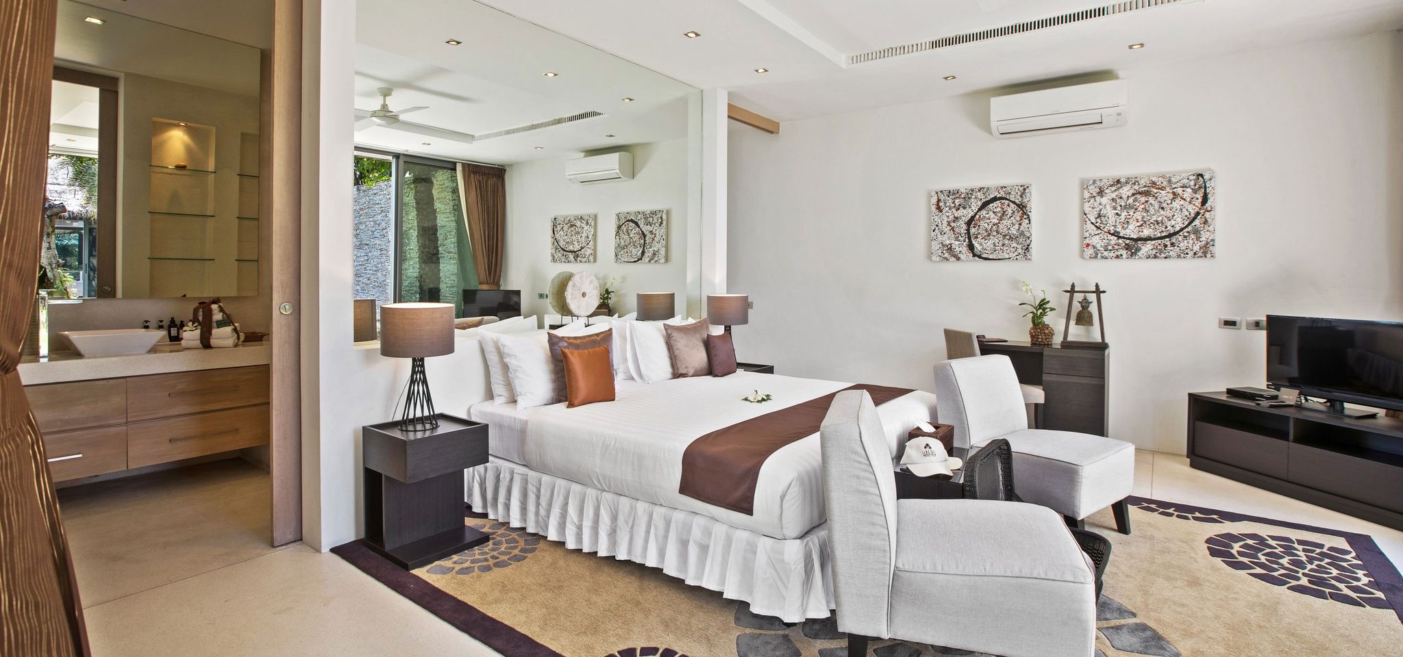 A modern bedroom with a large bed, bedside tables, a TV, and artwork on the walls.