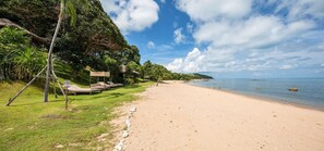 A beach with lounge chairs and a private sign.