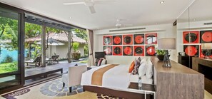 A modern hotel room with a large bed, a sitting area with a view of the ocean, and a wall decorated with red vinyl records. - Sangsuri Villa 3 (Koh Samui)