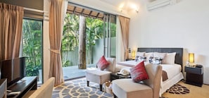 A modern hotel room with a large bed, a sofa, a TV, and a balcony with a view of greenery.