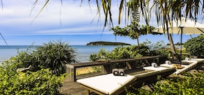 Una terraza de madera con sillones de descanso y vista al mar.
