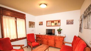 A living room with a wooden sofa set, a wooden coffee table, and a television on a wooden cabinet.