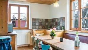 Eine Küche mit Holzausstattung, einem Esstisch, Stühlen, einem Blumentopf und einem Fenster mit Aussicht.