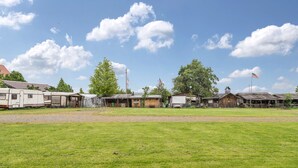 Ein Campingplatz mit Wohnmobilen, Holzhütten und einer Wiese.