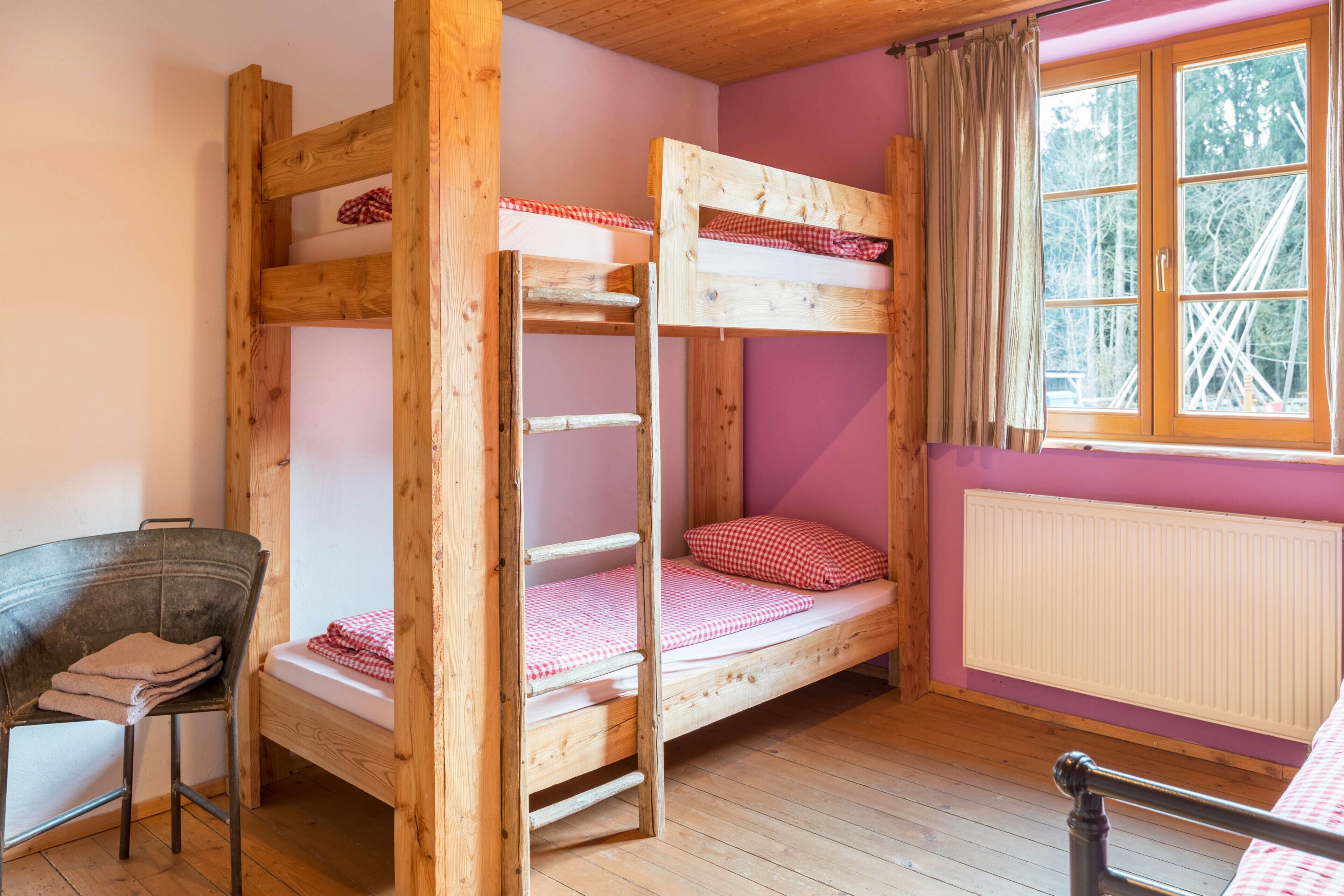 Une chambre avec un lit superposé, une fenêtre, une chaise et un radiateur.
